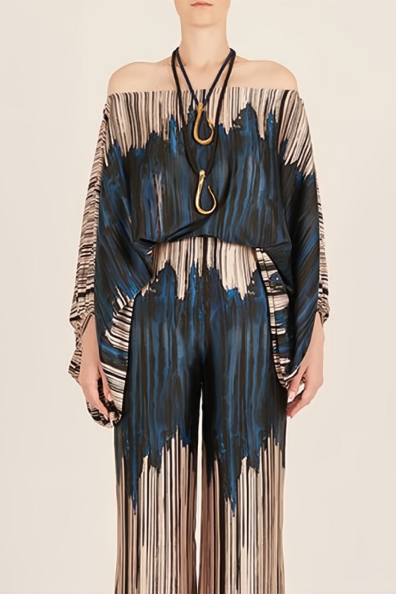 Woman wearing off-shoulder blue and beige abstract print silk jumpsuit