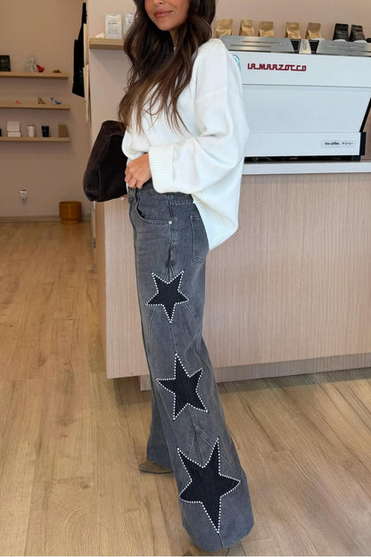 Woman wearing light wash wide leg jeans with star appliqués