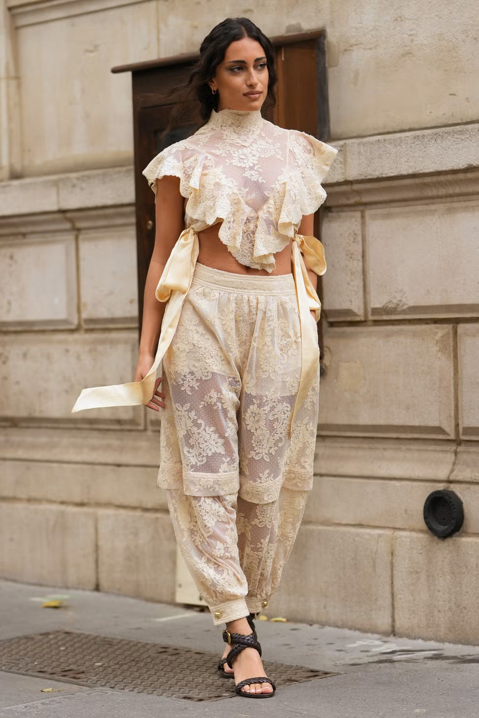 Woman in cream lace crop top and jeans on city street