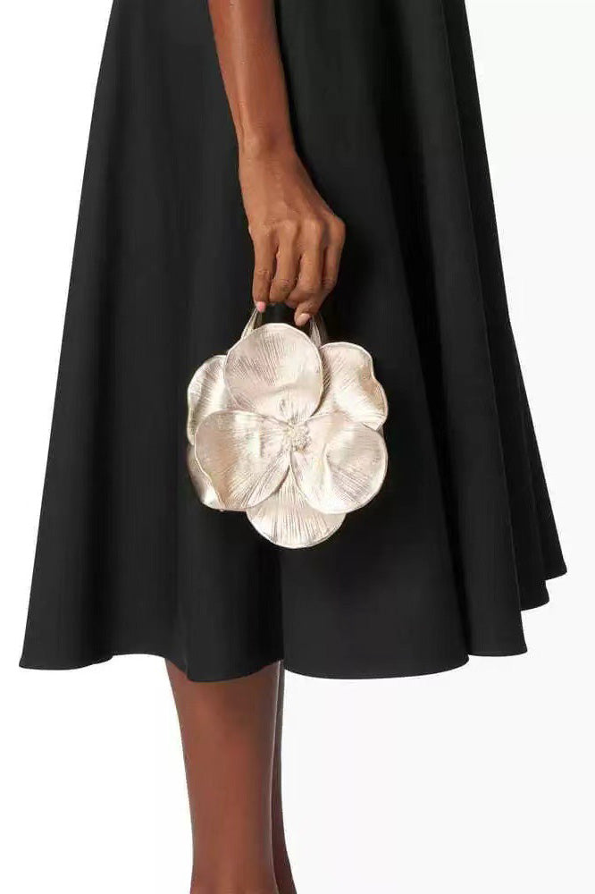 Woman in pink floral chiffon dress holding a red flower-shaped purse