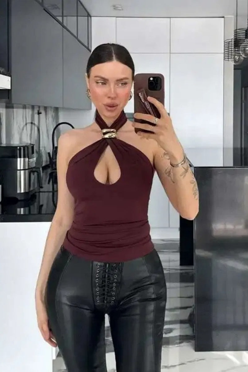 Woman wearing a black jersey halter top with gold hardware detail.