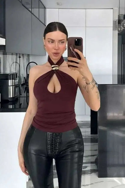 Woman wearing a black jersey halter top with gold hardware detail.