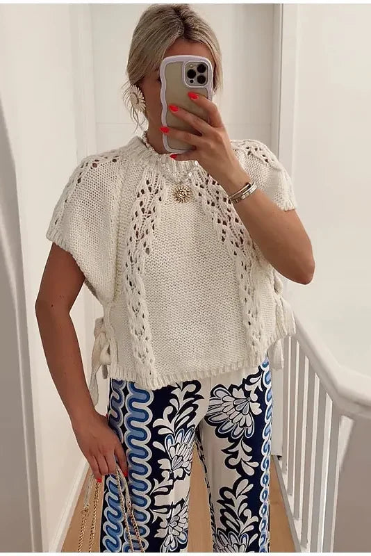 Woman in ivory crochet poncho with patterned pants
