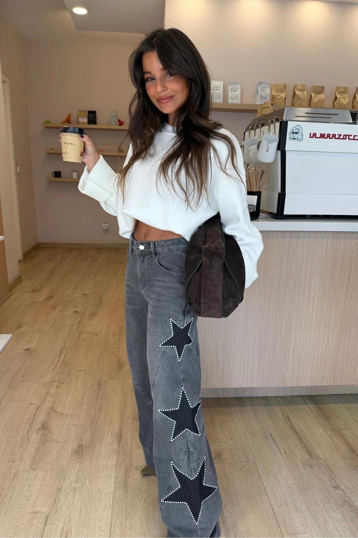 Woman wearing light wash wide leg jeans with star appliqués