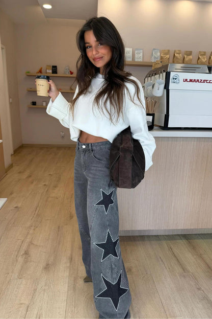 Woman wearing light wash wide leg jeans with star appliqués