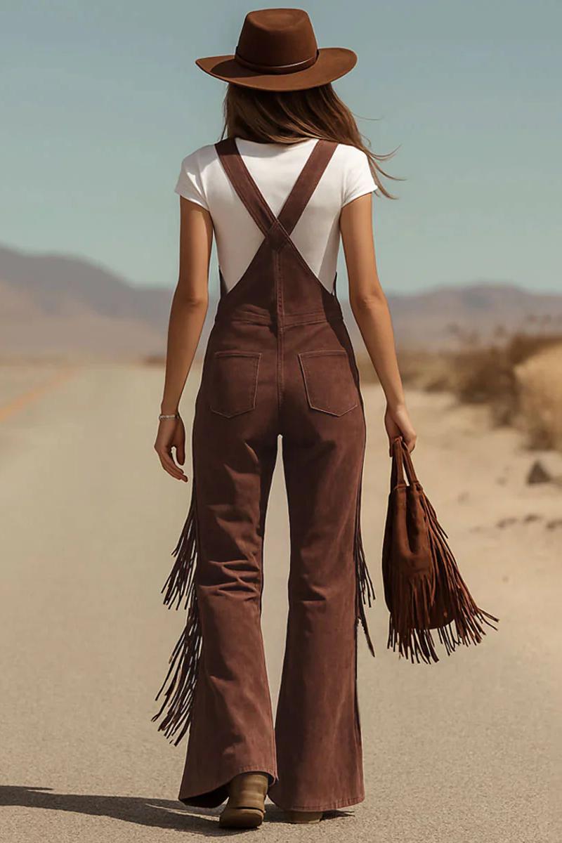 Woman in brown suede fringe overalls and hat walking in desert landscape