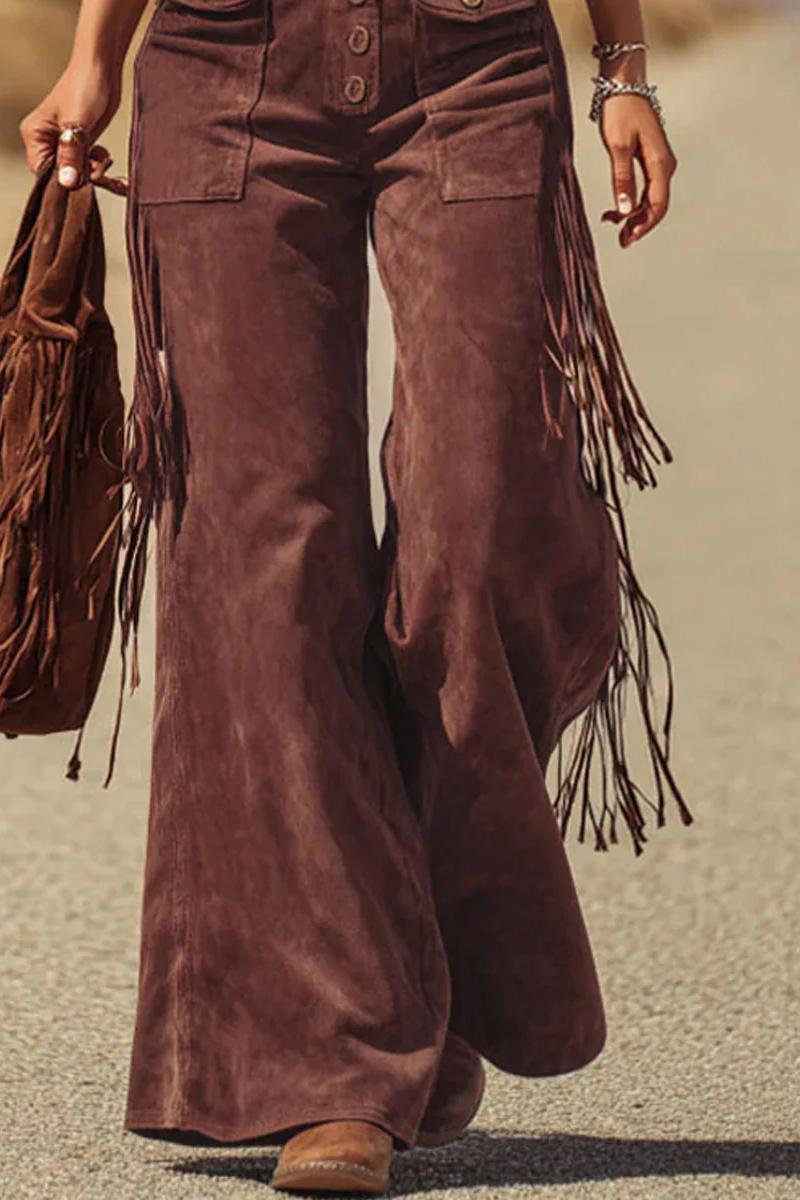 Woman in brown suede fringe overalls and hat walking in desert landscape