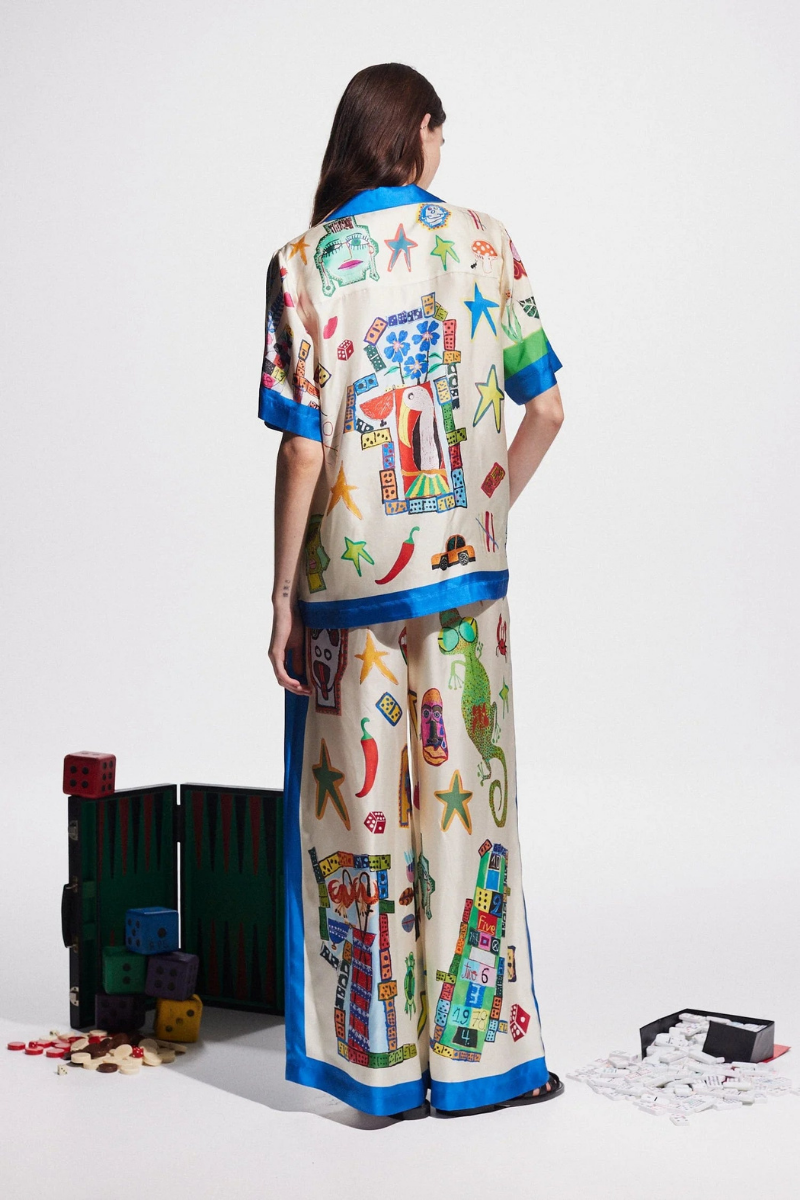 Woman in ivory silk pajama set with blue trim and novelty print