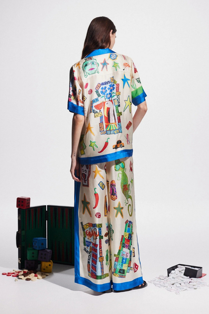 Woman in ivory silk pajama set with blue trim and novelty print