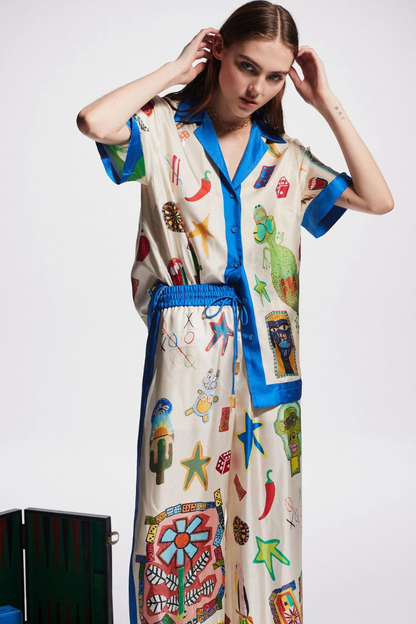 Woman in ivory silk pajama set with blue trim and novelty print