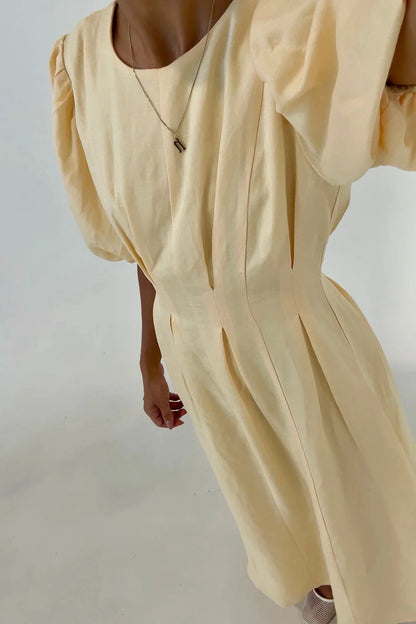 Woman in pale yellow linen maxi dress with puff sleeves