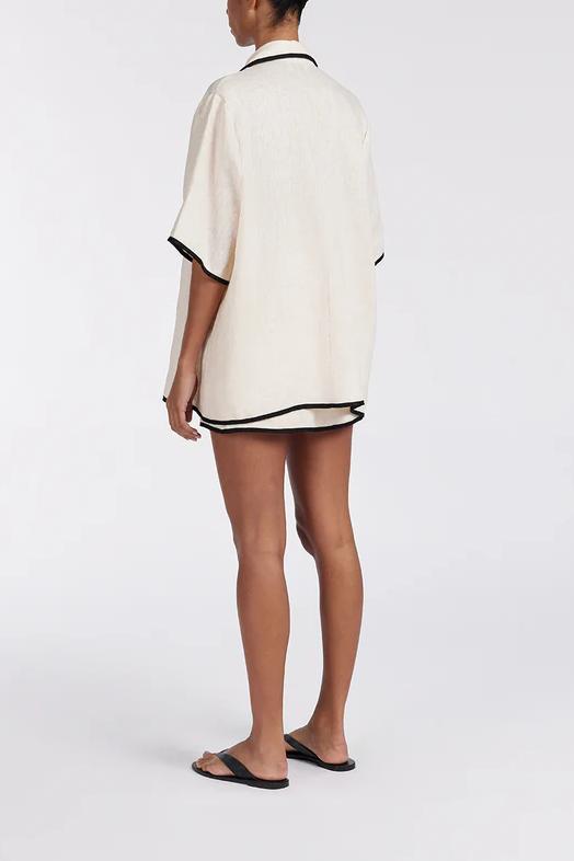 Woman wearing cream linen short set with black trim