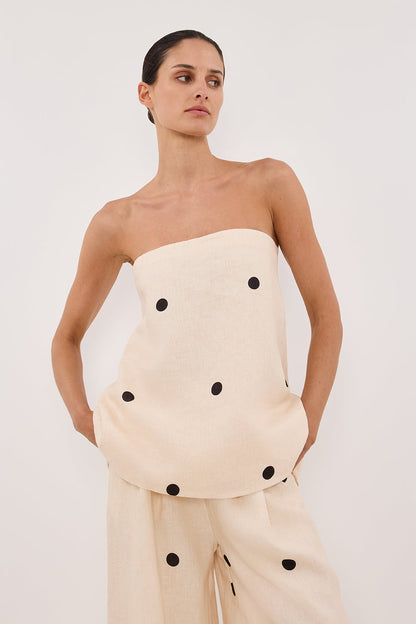 Woman in cream linen polka dot strapless top and wide leg pants