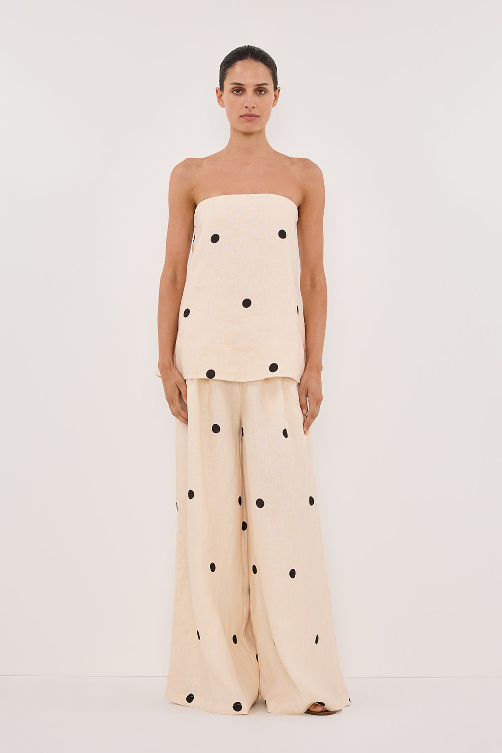Woman in cream linen polka dot strapless top and wide leg pants