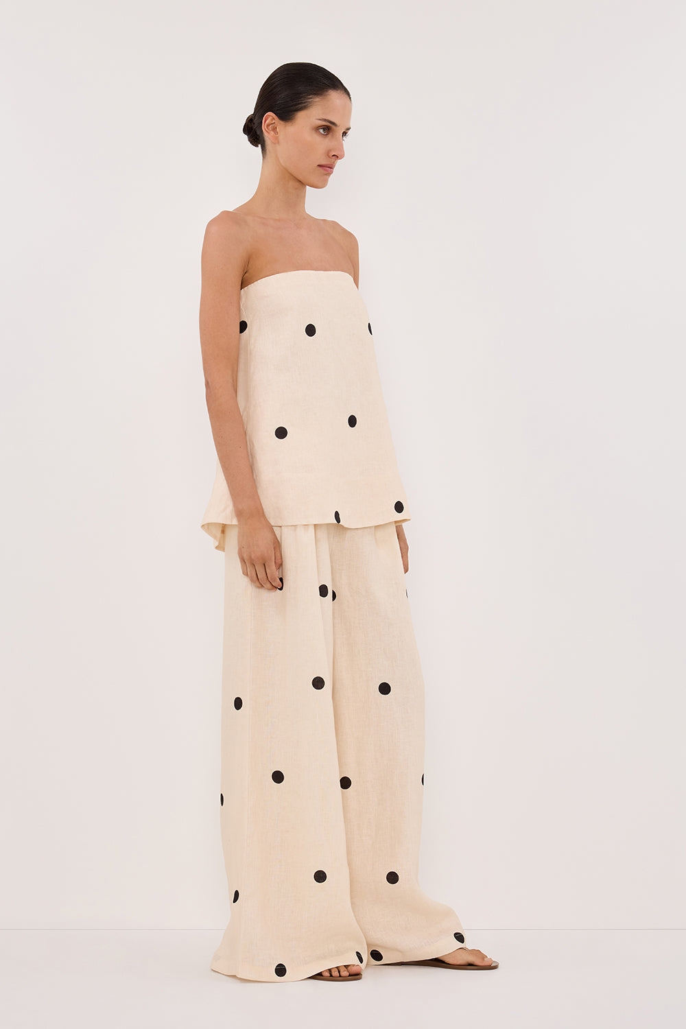 Woman in cream linen polka dot strapless top and wide leg pants