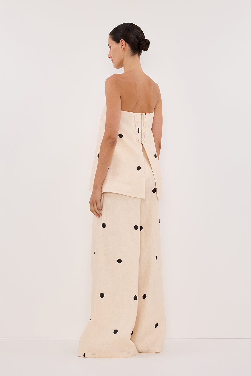 Woman in cream linen polka dot strapless top and wide leg pants