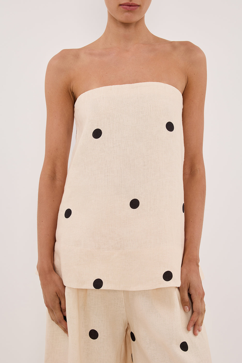 Woman in cream linen polka dot strapless top and wide leg pants