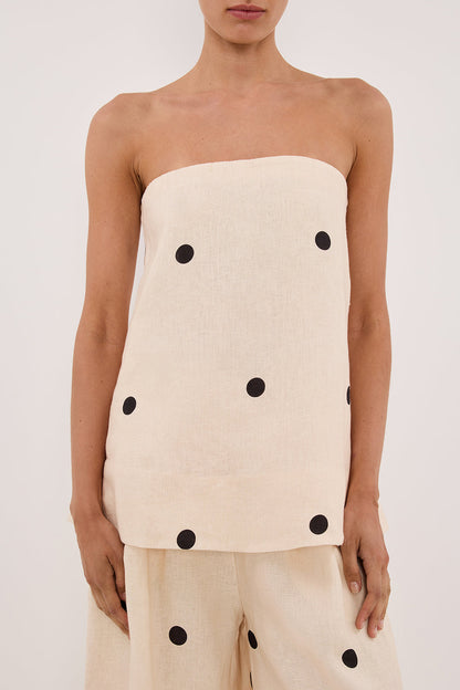 Woman in cream linen polka dot strapless top and wide leg pants