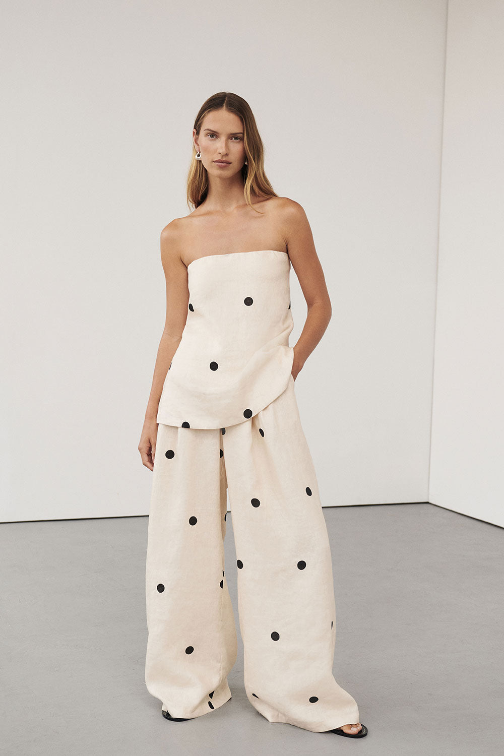 Woman in cream linen polka dot strapless top and wide leg pants