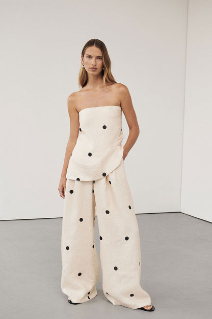 Woman in cream linen polka dot strapless top and wide leg pants