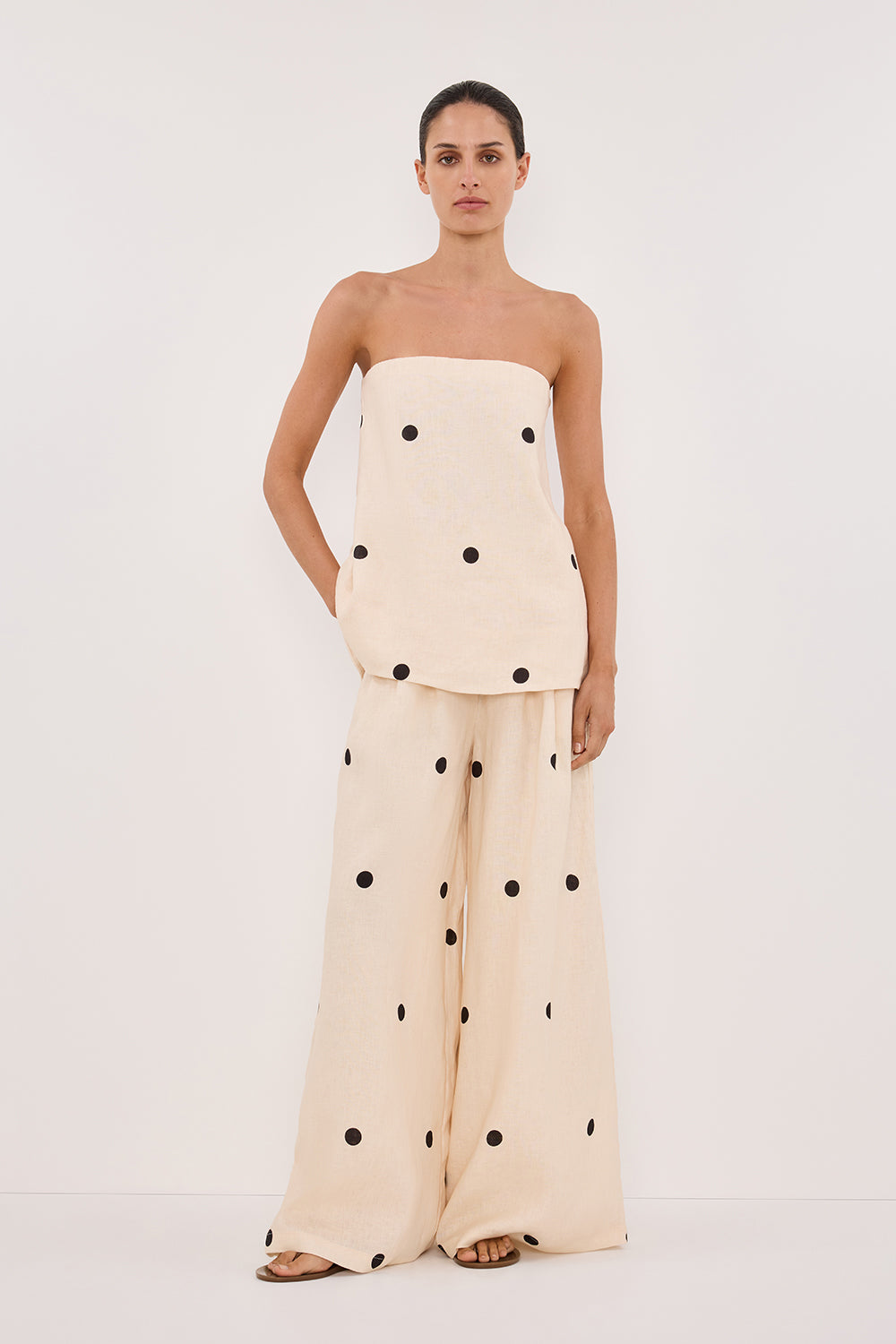 Woman in cream linen polka dot strapless top and wide leg pants