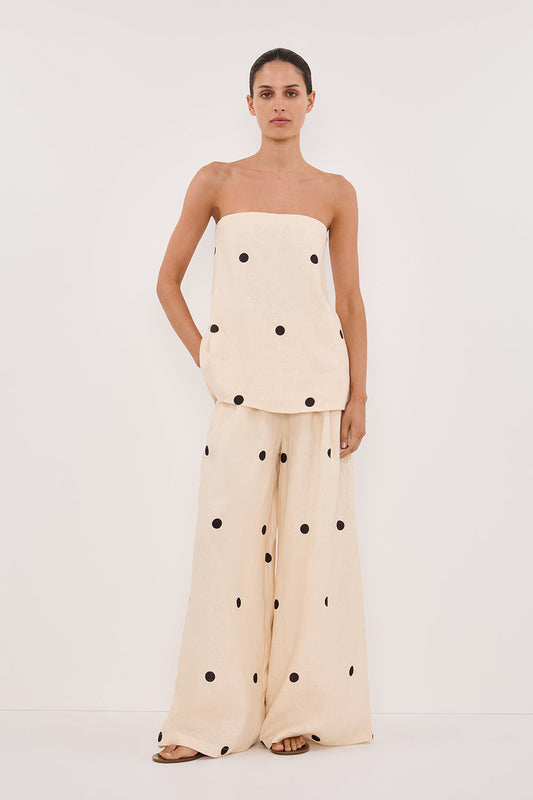 Woman in cream linen polka dot strapless top and wide leg pants