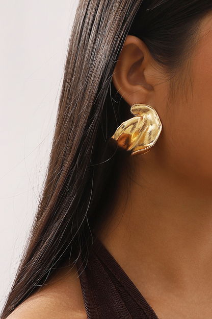 Close up of a gold abstract stud earring on an ear