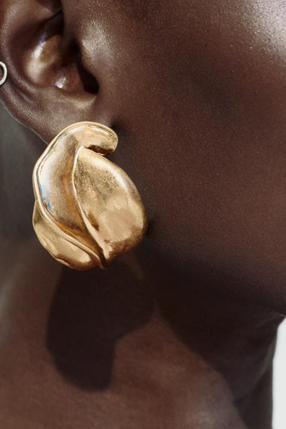 Close up of a gold abstract stud earring on an ear