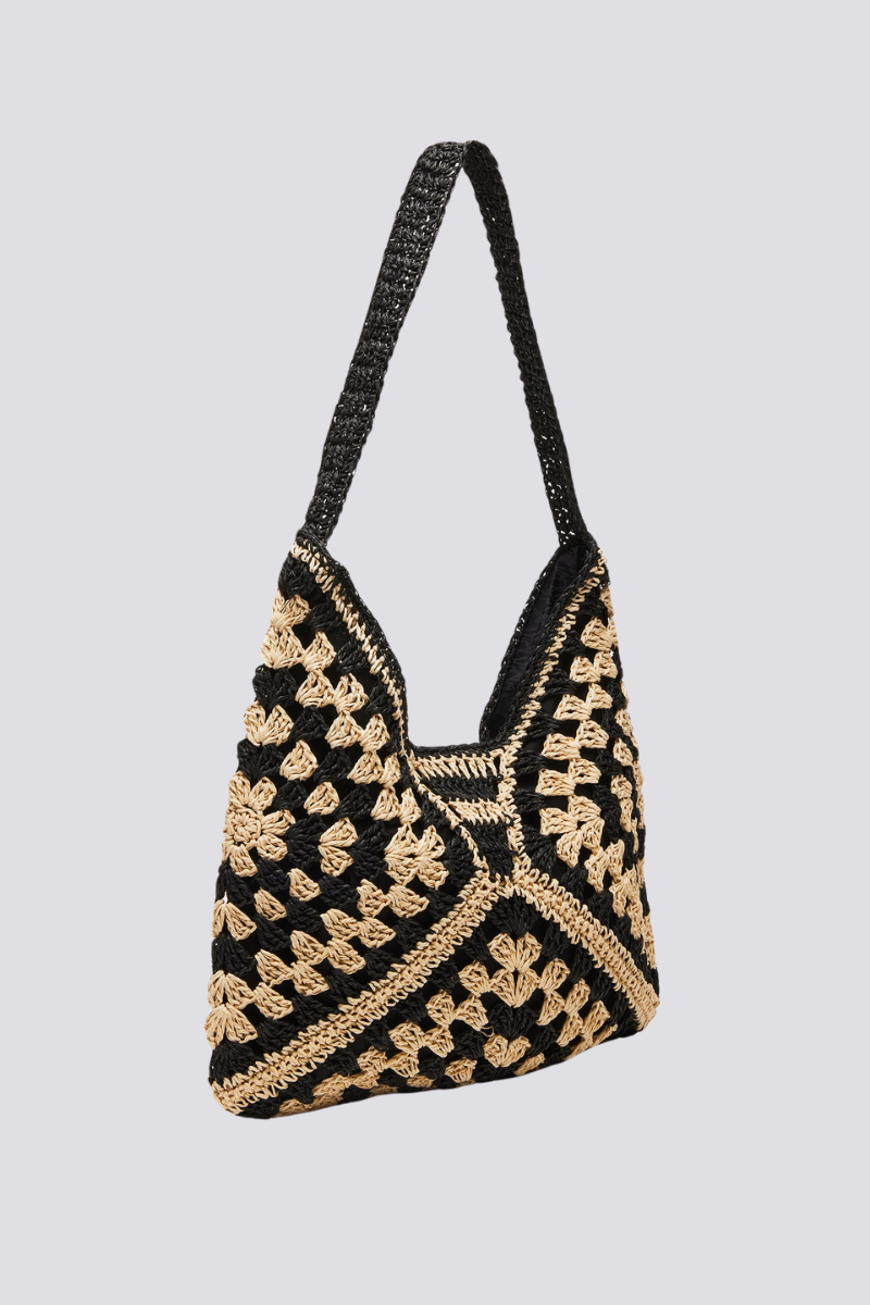 Woman holding a black and beige checkerboard crochet tote bag