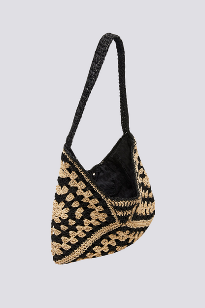 Woman holding a black and beige checkerboard crochet tote bag