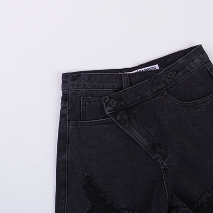 Woman wearing light wash denim shorts with asymmetrical waist and distressed hem.