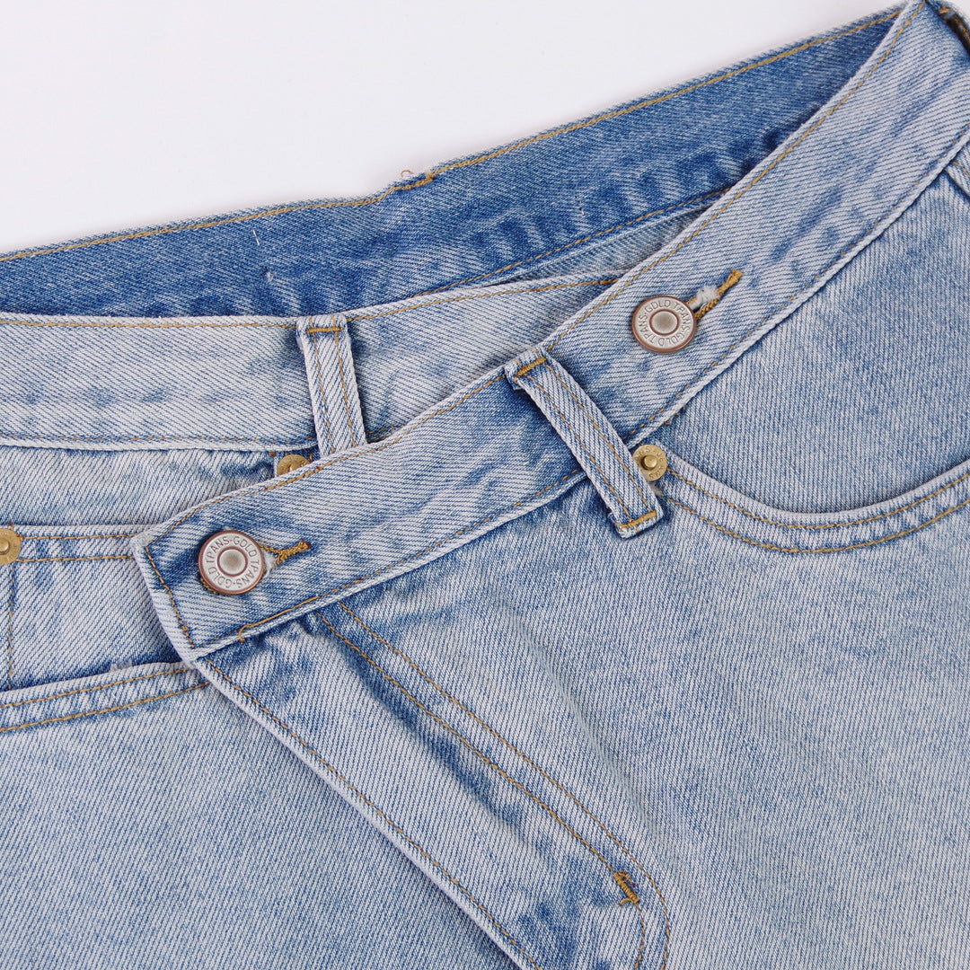 Woman wearing light wash denim shorts with asymmetrical waist and distressed hem.