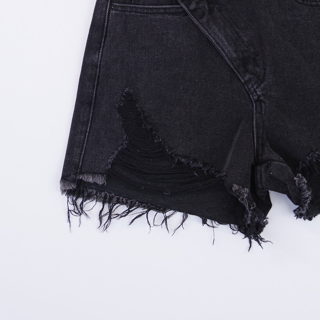 Woman wearing light wash denim shorts with asymmetrical waist and distressed hem.