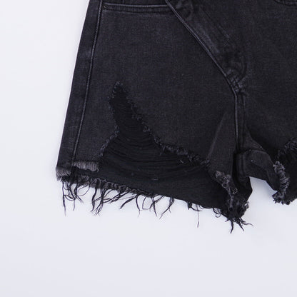 Woman wearing light wash denim shorts with asymmetrical waist and distressed hem.