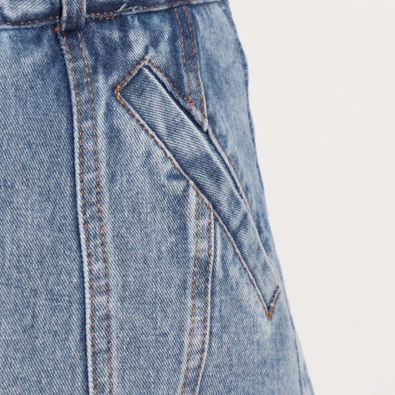 Woman wearing light wash denim skort with button detail