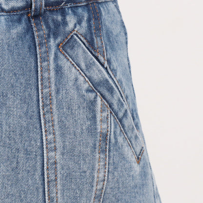 Woman wearing light wash denim skort with button detail