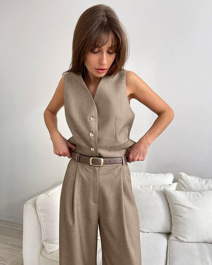 Woman in gray wool blend vest and wide leg pants holding a coffee cup and design book.
