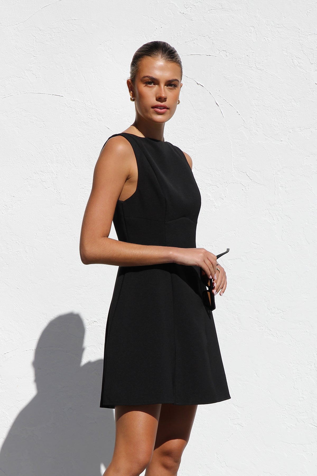 Woman in black sleeveless woven mini dress