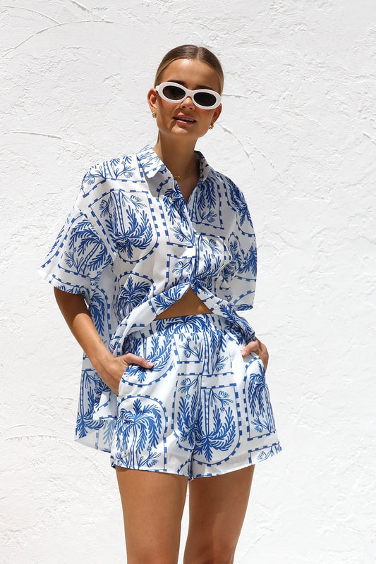 Woman in blue and white palm tree print shirt and shorts set