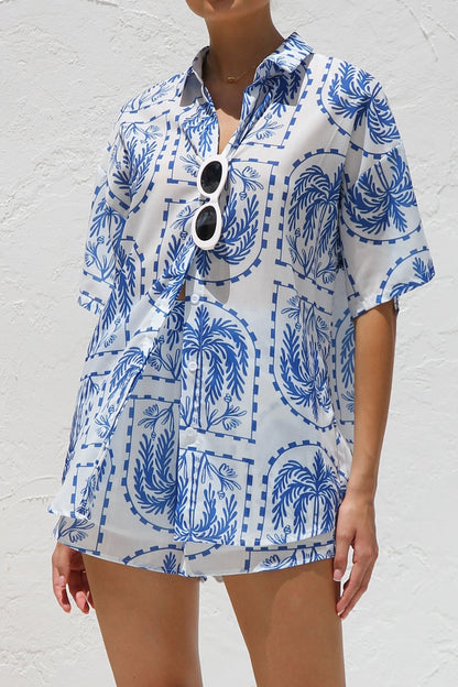 Woman in blue and white palm tree print shirt and shorts set