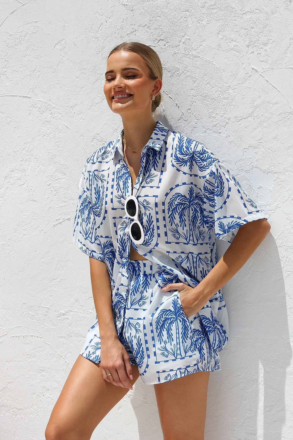 Woman in blue and white palm tree print shirt and shorts set