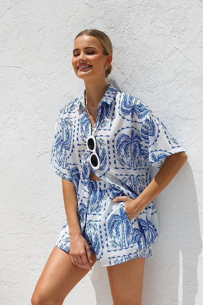 Woman in blue and white palm tree print shirt and shorts set