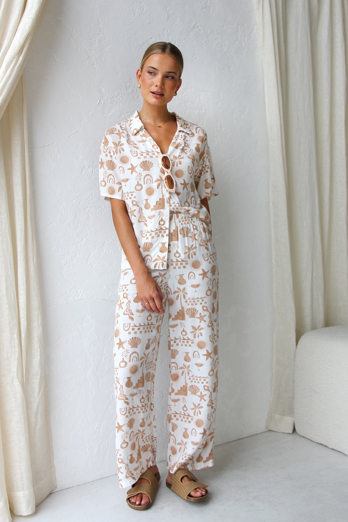 Woman wearing beige linen pajama set with beach-themed print