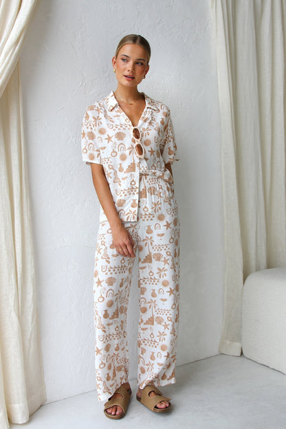 Woman wearing beige linen pajama set with beach-themed print