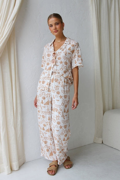 Woman wearing beige linen pajama set with beach-themed print