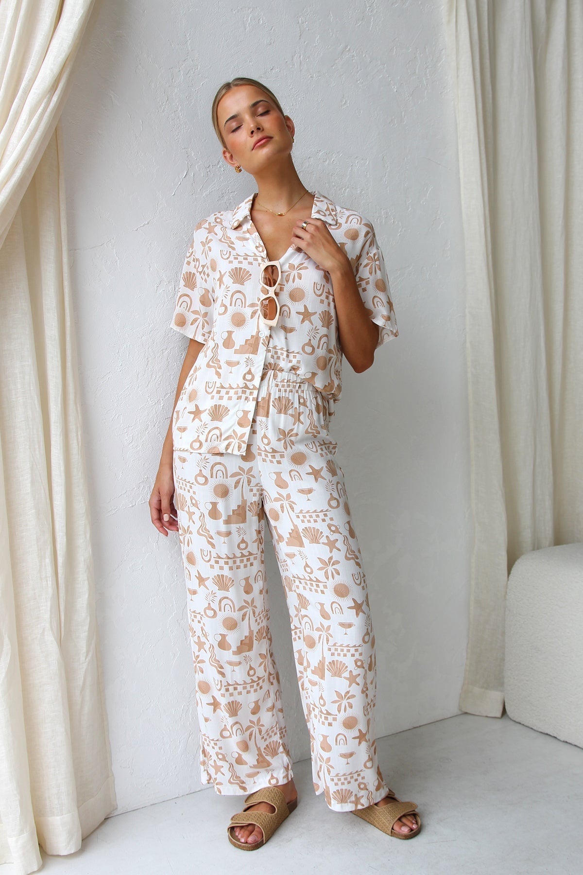 Woman wearing beige linen pajama set with beach-themed print