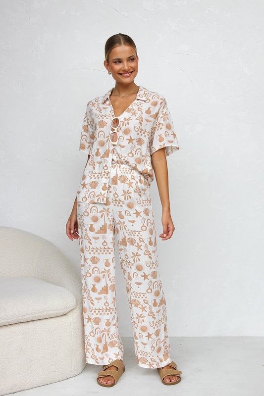 Woman wearing beige linen pajama set with beach-themed print