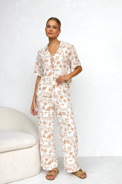 Woman wearing beige linen pajama set with beach-themed print