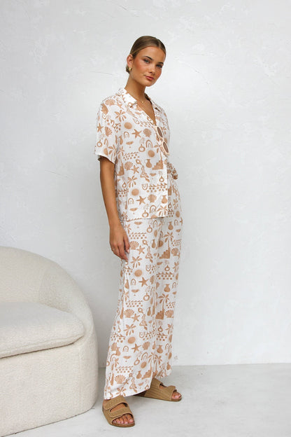 Woman wearing beige linen pajama set with beach-themed print