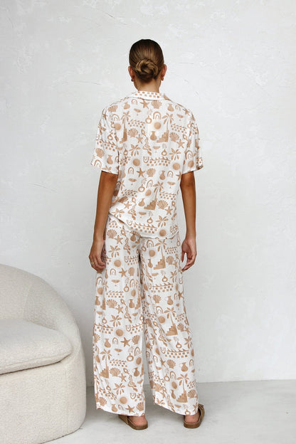 Woman wearing beige linen pajama set with beach-themed print